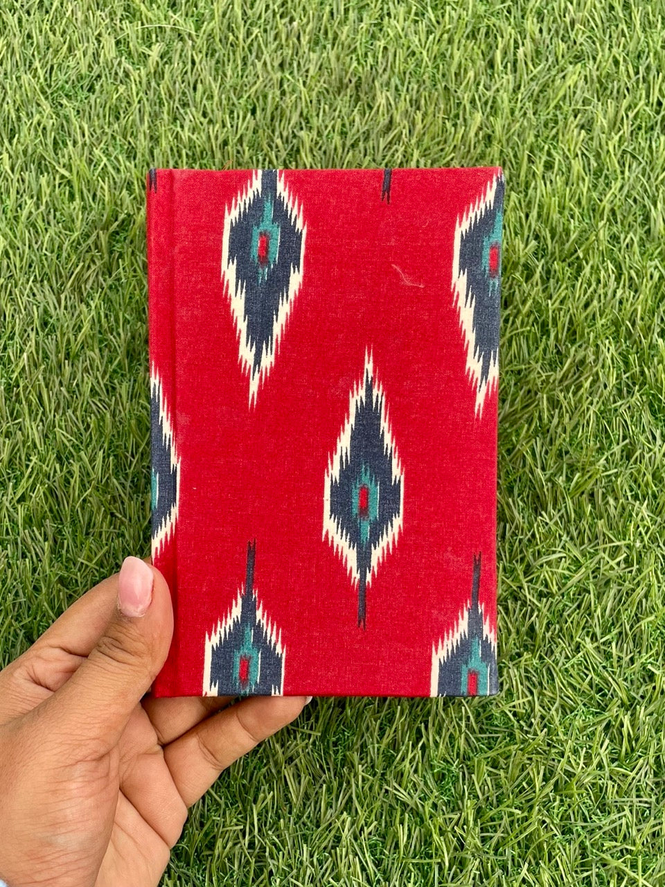 Red Ikat designed handmade plantable journal diary on grass view, designed for journalers. Perfect for writing, sketching, and planning.